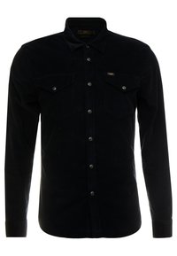 Czarna koszula z korduroy z długimi rękawami, zapięciem na guziki z przodu, dwoma kieszeniami na piersi oraz markową etykietą. Posiada klasyczny kołnierz oraz prążkowaną teksturę.