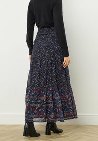 Czarna spódnica maxi w kwiaty z marszczoną talią i warstwowym fasonem. Charakteryzuje się połączeniem niebieskich i burgundowych kwiatów z kontrastowymi brzegami.