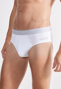 Mutande bianche a slip realizzate in cotone, con un elastico grigio chiaro che presenta il nome del marchio "SLOGGI" in un carattere discreto sul lato.