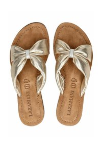 Sandales en or avec une semelle intérieure texturée de couleur beige et un grand nœud métallique sur le bout. Cuir lisse avec des accents de couture.