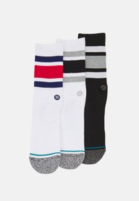 Drei Paar Socken mit geripptem Muster und kontrastierenden Streifen. Die Farben umfassen Weiß, Rot, Marineblau, Grau und Schwarz mit einer gepunkteten Ferse.