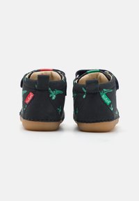Chaussures pour enfants en velours noir avec des motifs de feuilles de palmier verts, une semelle en caoutchouc beige, et des bandes Velcro pour un attachement facile.