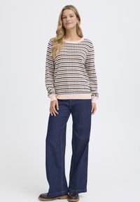 Viegls svītrains džemperis ar garām piedurknēm krēmkrāsā, tumši zilā un brūnā tonī. Kombinēts ar platām zilām džinsa biksēm un brūniem akcentiem.