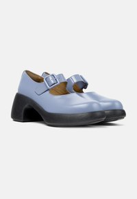 Light blue leather shoes with cutouts, prominent buckles on the straps, and a textured black platform heel. Smooth finish, rounded toe design.