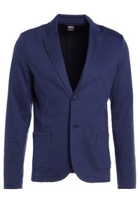 Námornícky modrý blejzr vyrobený z jemné látky. Obsahuje vykrojený límec, dvě přední kapsy a dva knoflíky. Hladká textura s přizpůsobeným střihem.