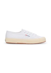 Sneakers bianchi in tela con profilo basso, dotati di una suola in gomma testurizzata, design con lacci e un piccolo logo sul lato.