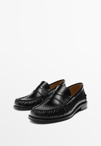 Black leather loafers with a rounded toe, stitched detailing, and a penny slot accent. Smooth texture and a low stacked heel.