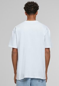 Hvid bomulds t-shirt med en afslappet pasform, korte ærmer, rund hals og en glat tekstur, set fra ryggen.