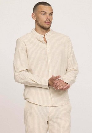 Chemise beige clair à boutons avec rayures verticales et col à bandes, fabriquée en tissu texturé. Manches longues, silhouette ajustée.