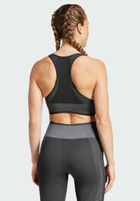 Svart sportbh med racerback-design och texturerade accenter, kombinerad med högmidjade leggings med grå detaljer och mönster.