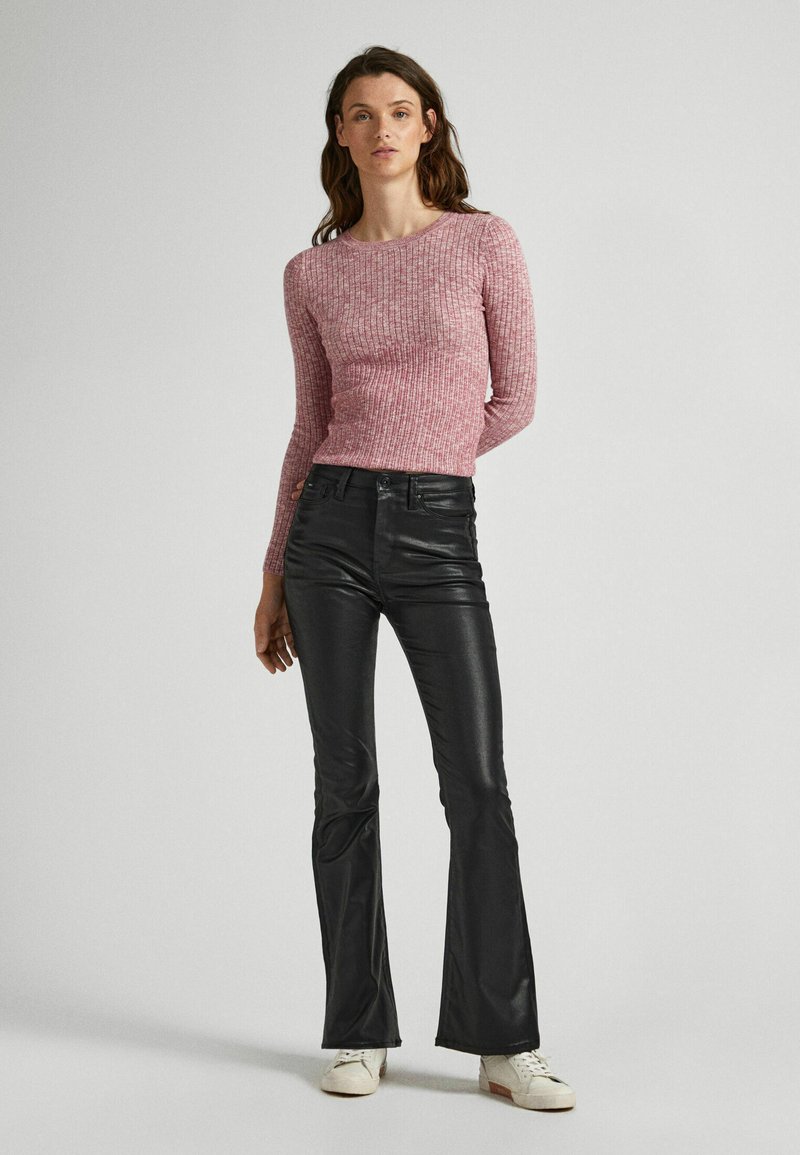 Top a maniche lunghe rosa a costine abbinato a pantaloni in pelle neri a palazzo e sneakers bianche. Il top ha un design aderente e una finitura testurizzata.