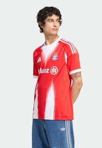 Maillot de sport en dégradé rouge et blanc avec des manches courtes, arborant le logo du Bayern Munich et des bandes Adidas sur les épaules.