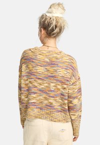 Sweter z teksturowanego dzianiny w ciepłych odcieniach żółtego, brązowego i fioletowego. Luźny krój z opuszczonymi ramionami i prążkowanym dołem. Odpowiedni na codzienne noszenie.
