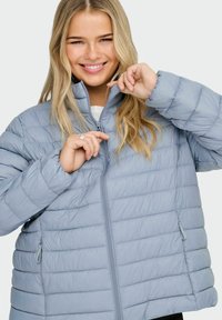 Světle modrá péřová bunda s hladkou texturou, horizontálním prošíváním, vysokým límcem a předním zapínáním na zip; obsahuje boční kapsy.