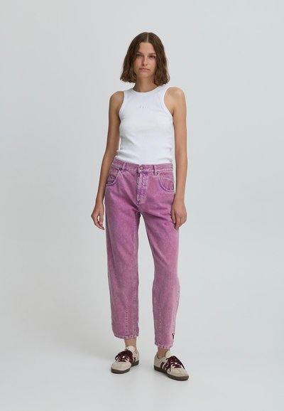 Top alb fără mâneci, blugi roz denim cu labe late și pantofi bej cu sireturi mahon. Are un croi lejer și un design cu cinci buzunare.