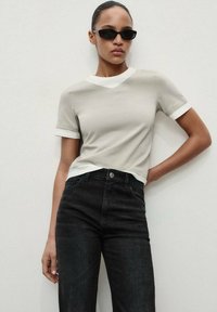 Gray t-shirt with a white collar, short sleeves, and a fitted style, paired with high-waisted black jeans. Matte texture throughout.