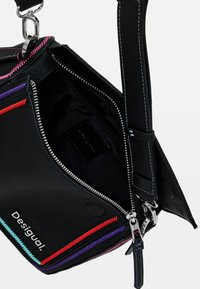 Borsa in pelle nera con zip colorate in rosa, rosso, viola e turchese. Presenta un compartimento con zip e una tracolla robusta. Logo sulla parte anteriore.