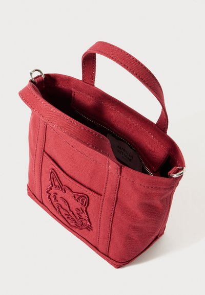 Saco de lona vermelho com bordado de uma raposa na frente. Apresenta um fecho de correr na parte superior e uma pega curta para fácil transporte.