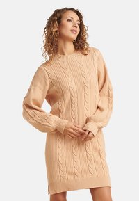 Vestito maglione lavorato a maglia in morbido pesca, con dettagli a trecce, maniche lunghe, polsini a coste e spaccature laterali per maggiore stile e comfort.