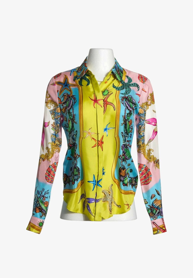 Blouse boutonnée à manches longues avec imprimé coloré sur le thème de la mer comprenant des étoiles de mer, des coquillages et du corail sur fond jaune, bleu, rose et blanc.