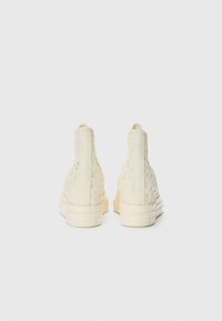 Lisseopp høye sneakers i krem med lisse-overlegg, gummisåler og flat hæl. Har teksturert detaljering på overdelen.