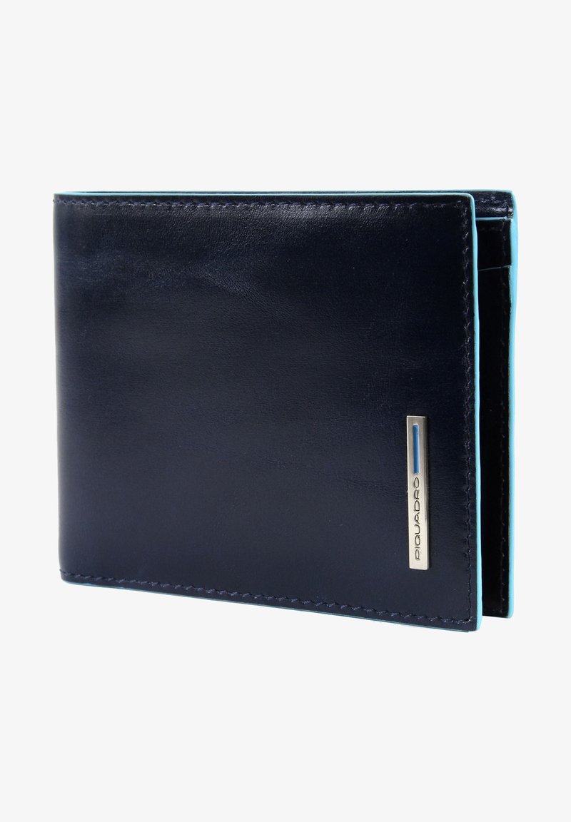 Billetera de cuero azul marino con textura suave, costuras azul claro y un acento de logotipo de metal plateado. Forma rectangular, diseño de doble pliegue.