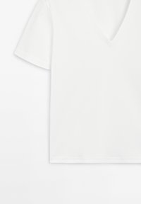 Weißes Kurzarm-T-Shirt mit tiefem V-Ausschnitt, aus weicher Baumwolle gefertigt, zeichnet sich durch klare Linien und eine glatte Textur aus.