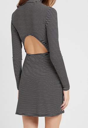 Vestito a righe bianche e nere con scollatura alta, maniche lunghe e dettaglio schiena scoperta, caratterizzato da un corsetto aderente e gonna svasata.