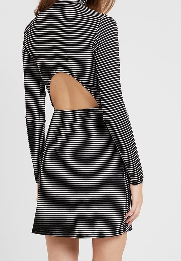 Mustavalkoraidallinen mekko, jossa on korkea kaula-aukko, pitkät hihat ja leikattu selkäosa, jolloin se on tiukka yläosasta ja hulmuava hame.