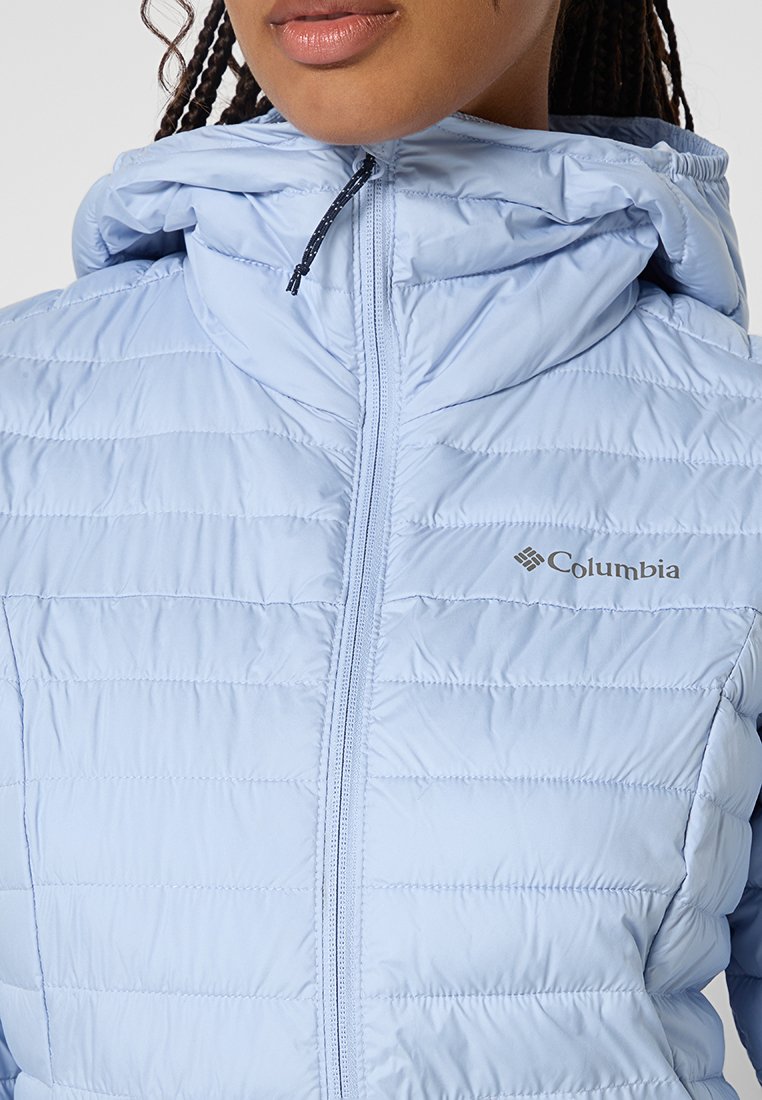 Giacca isolante azzurro chiaro con zip frontale e cappuccio, caratterizzata da un design trapuntato, logo Columbia e dettagli elastici attorno al viso.