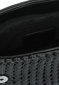Bolso de cuero trenzado negro con un acabado suave, que presenta un bolsillo interior y un cierre elegante. Interior forrado de tela negra.