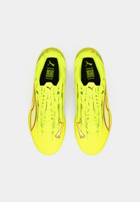 Lyse gule sportssko med et elegant design, tekstureret overdel og røde detaljer. Har et logo nær snørebåndene og en QR-kode på indersålen.