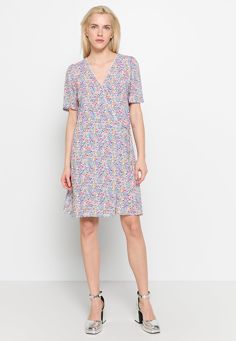 Bloemen wikkeljurk in lichte stof met korte mouwen, v-hals en een uitlopende zoom. De belangrijkste kleuren zijn roze, blauw en geel.