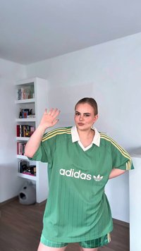 Jersey verde Adidas oversize con colletto e strisce bianche. Il jersey presenta righe verticali e un logo prominente sul davanti.