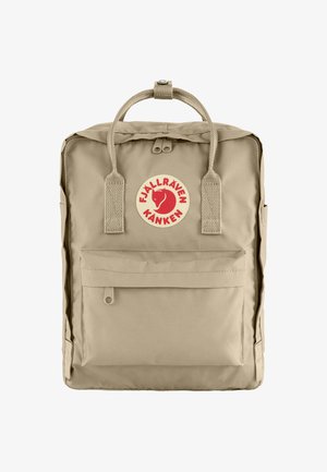 Beige Fjällräven Kanken Rucksack mit runder Form, vorderer Reißverschlusstasche und einem runden Logo-Patch mit einem roten Fuchs-Design.