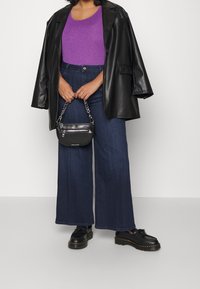 Svart läder oversized blazer, lila åtsittande topp, vida mörkblå jeans, svart handväska med kedjerygg, och svarta platåskor.