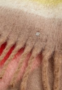 Wollen deken met een kleurverloop van geel naar roze, met franjes aan de randen en een klein metalen logo accent. Zachte, textuurrijke oppervlakte.