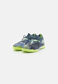 Scarpe sportive con tomaia in rete blu scuro, accenti verde neon, design a motivi e suola texturizzata. Presentano un sistema di chiusura con lacci e una vestibilità aderente.