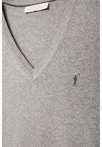 Pull gris clair col V avec petite figure noire brodée d'une personne tenant une trompette sur la poitrine et une étiquette Polo Club à l'intérieur du col.