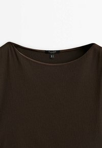 Ruskea lyhythihainen paita, jossa on leveä pyöreä kaula-aukko, valmistettu pehmeästä ja sileästä kankaasta. Sisällä näkyvä etiketti, jossa on koko ja hoito-ohjeet.