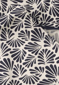Tessuto con sfondo crema caratterizzato da un motivo a foglia blu navy ripetuto. Il materiale è morbido con una texture liscia; i bordi sono rifiniti in modo ordinato.