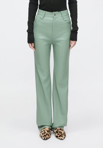 Pantaloni a gamba larga verde menta realizzati in un tessuto liscio, con vita alta e tasche anteriori, abbinati a scarpe slip-on con stampa leopardata.