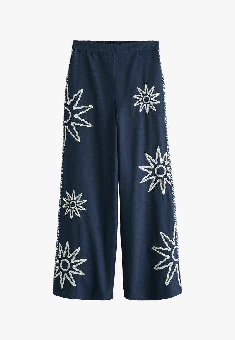 Pantalon large de marine avec taille élastique, présentant une grande broderie blanche en forme de rayons solaires à l'avant et des bandes latérales à motif.