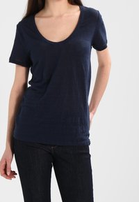 Marinblå kortärmad t-shirt med djup rund halsringning, tillverkad av ett mjukt, lätt material, med avslappnad passform och subtil textur.