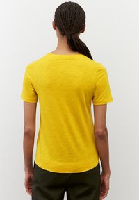 Gul kortærmet t-shirt med rund halsudskæring og en afslappet pasform. Teksturen virker blød med et subtilt meleret mønster.