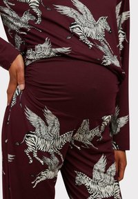 Maternity outfit in burgundy fabric featuring a print of flying zebras. The material is smooth with a stretchy texture, snug on the waist.