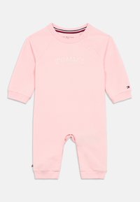 Salopetă pentru bebeluși de culoare roz deschis, fabricată dintr-un material moale, având guler rotund, mâneci lungi și logo-ul brodat "TOMMY HILFIGER" pe față.