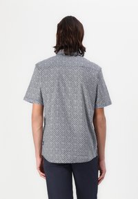 Cămașă cu mânecă scurtă, cu un model geometric alb și albastru, design cu guler și tiv drept. Fabricată dintr-un material ușor.