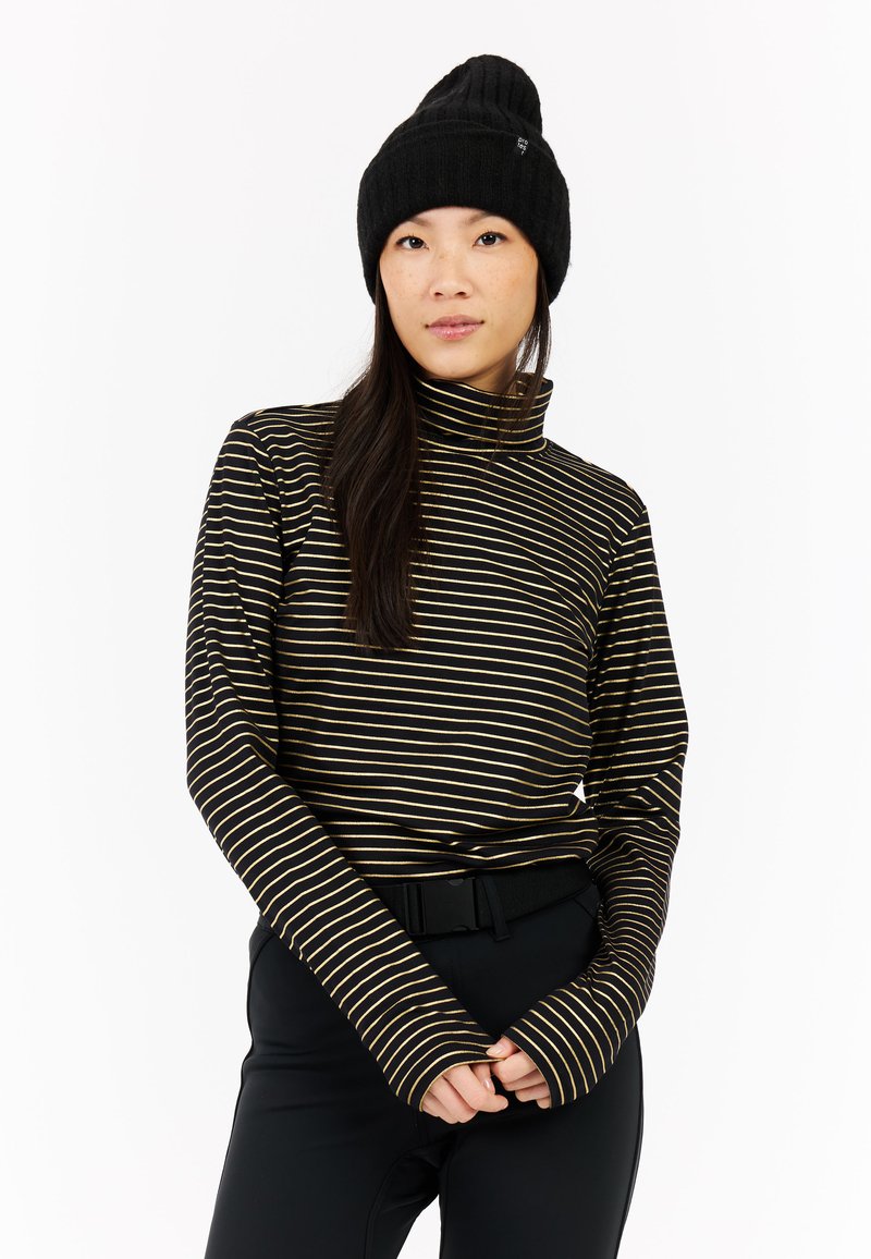 Haut à col roulé à manches longues noir et or à rayures, avec des manches allongées, porté avec un pantalon noir taille haute et un bonnet côtelé noir.