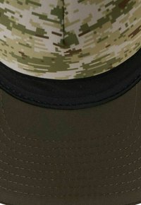 Tarnmütze mit strukturiertem, grün-beigem Obermaterial und einem schlichten schwarzen Schirm; strukturiertes Design mit gestickten Details.